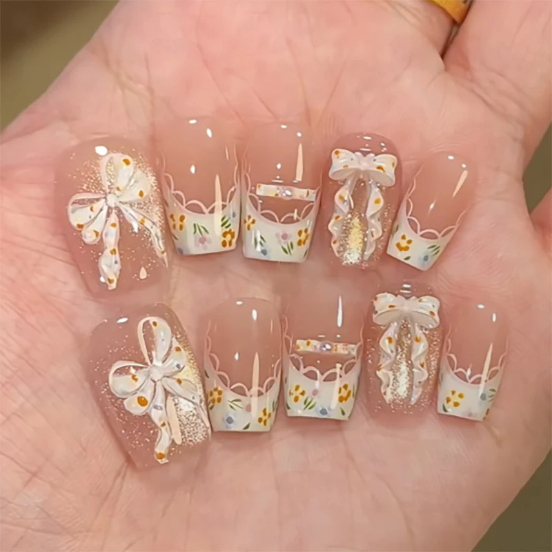 Kunstvolle Nagelverlängerungen mit floralem Design und Schleifenakzenten Karnz