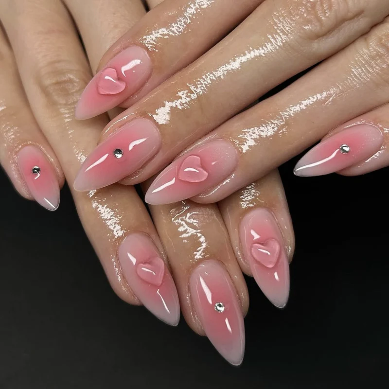 Kunstvolle Stiletto-Nägel mit Herzdesign und Glitzerakzenten Karnz