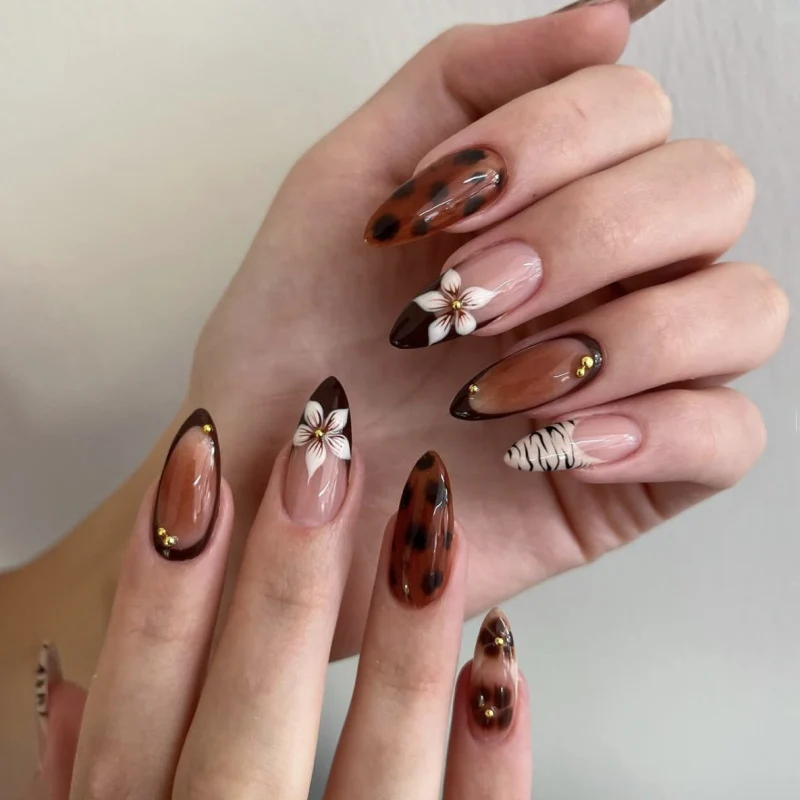 Kunstvolle Stiletto-Nägel mit eleganten Blumenmotiven und Glitzerakzenten Karnz