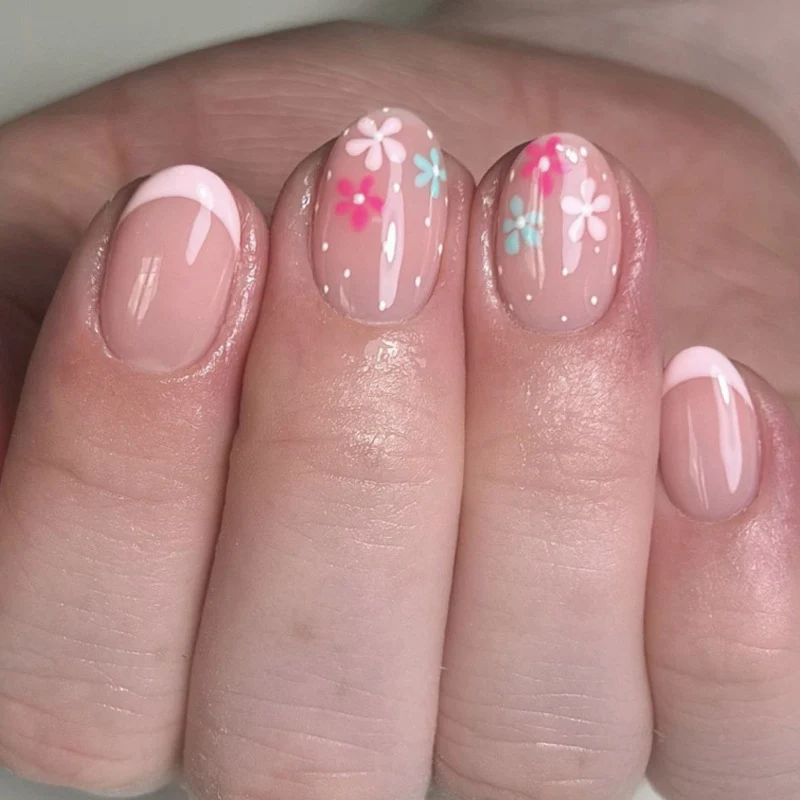 Kunstvolle Nagelverlängerungen mit bunten Blütenmotiven und Glitzer Karnz